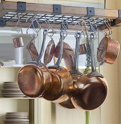 Ollas de cobre colgadas de un estante en una cocina.