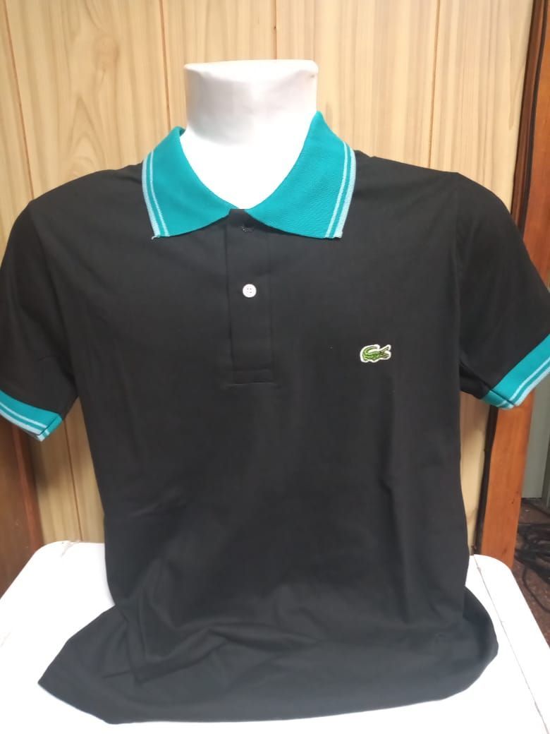 Camisa polo negra con cuello y mangas color verde azulado y logotipo de cocodrilo.