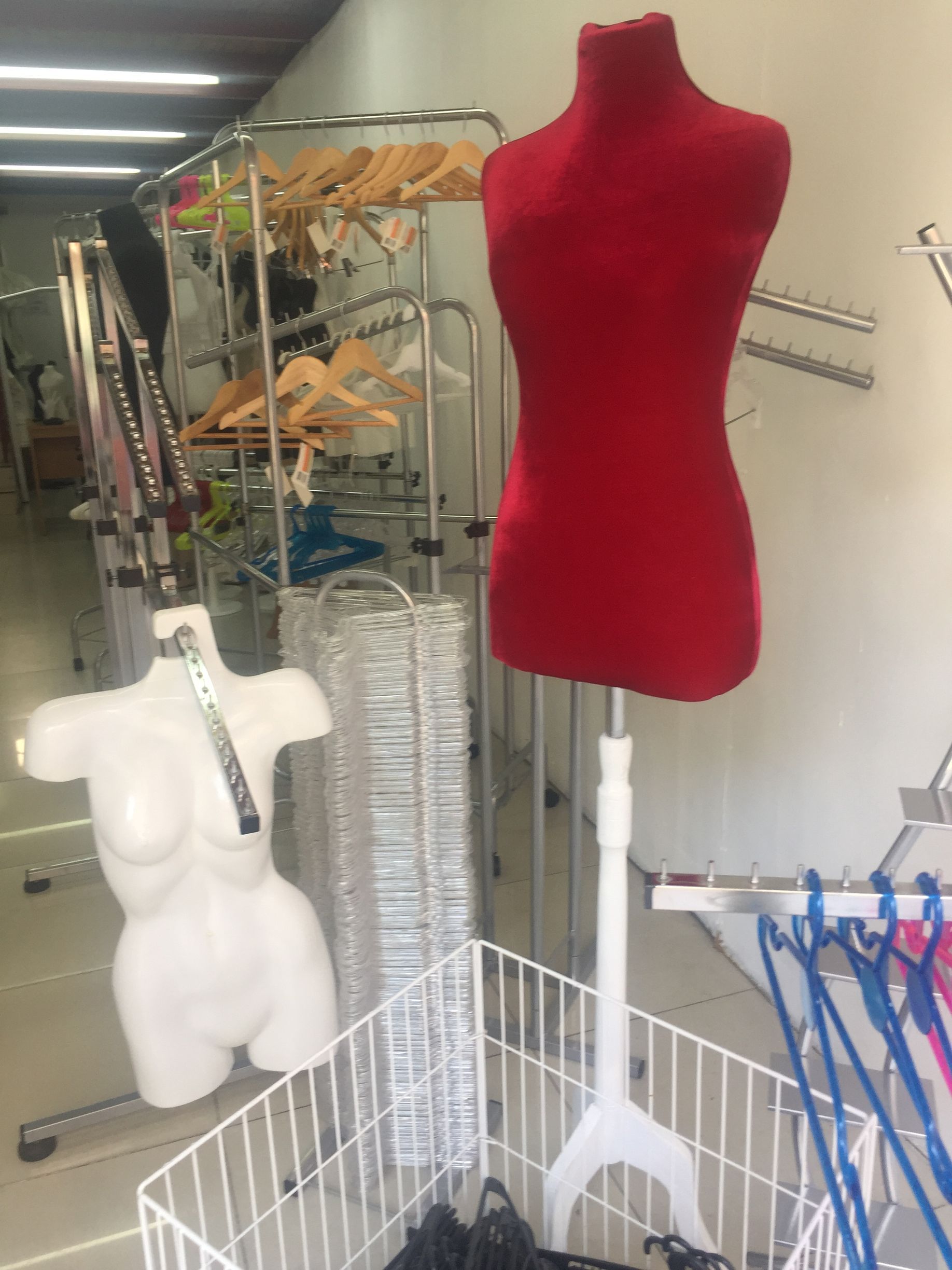 Maniquíes rojos y blancos con percheros y perchas en un establecimiento minorista.