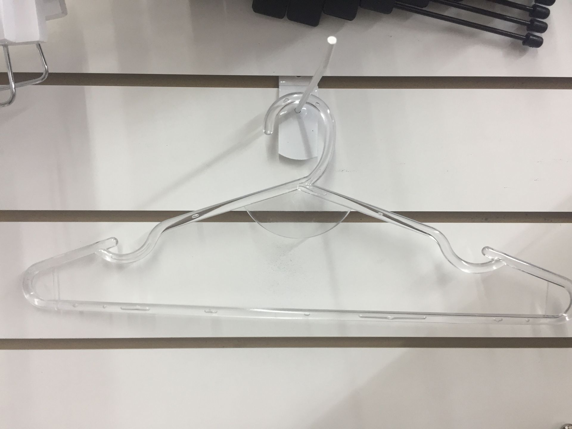 Percha de ropa de plástico transparente colgada en una pared de listones blancos.