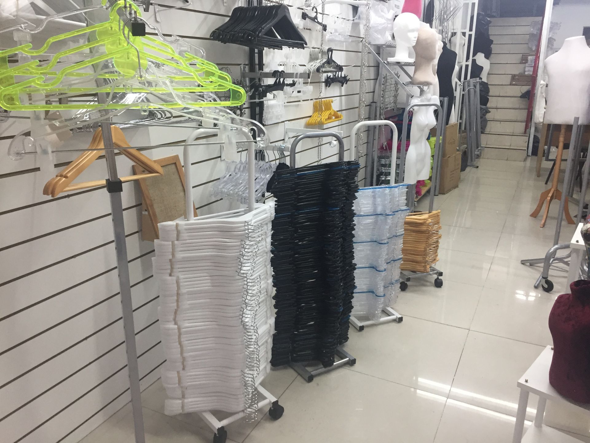 Interior de tienda de ropa con filas de perchas y estantes llenos de prendas y accesorios.