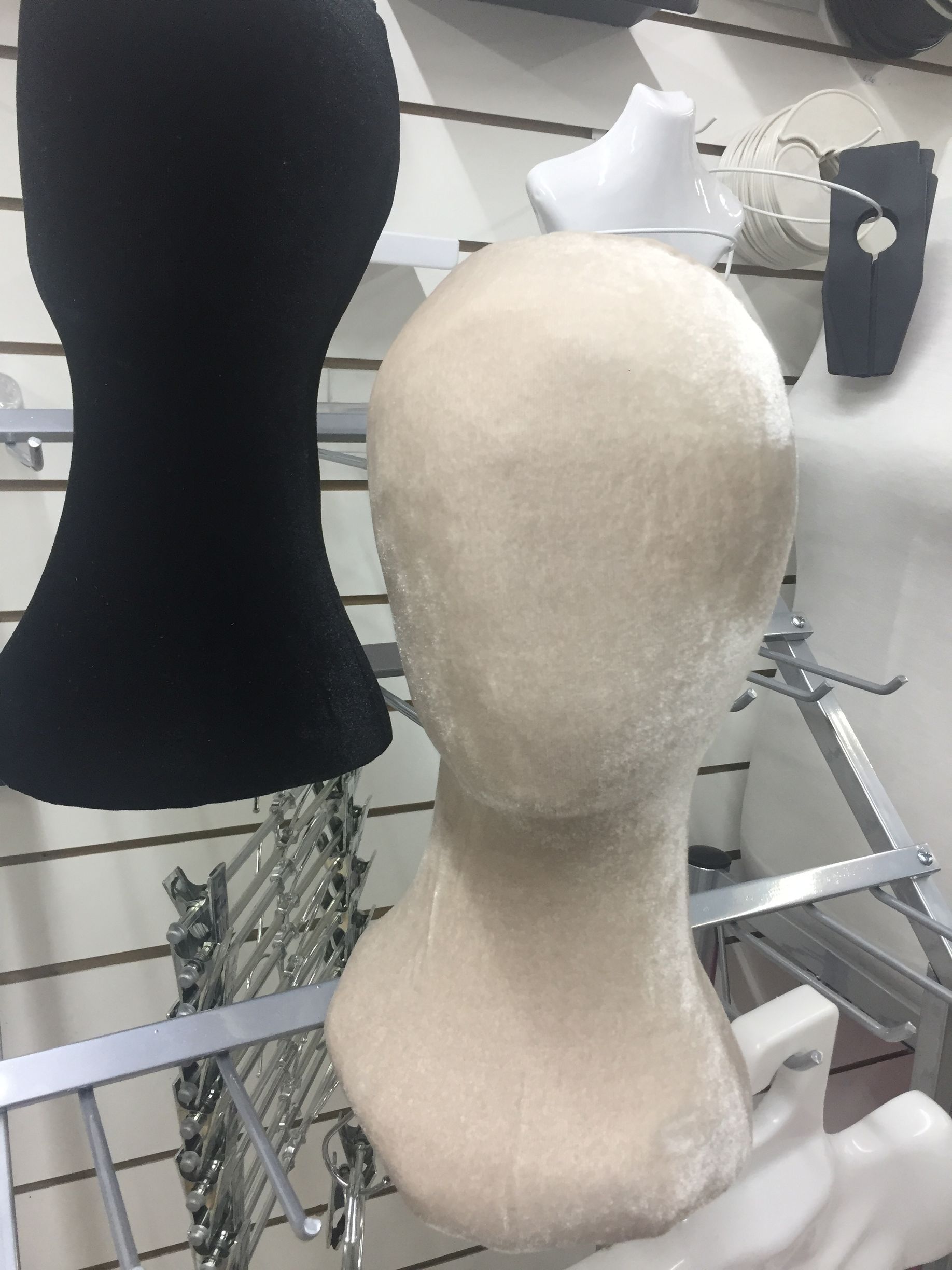 Exhibición de cabezas de maniquí, incluidas formas negras y beige, en un estante.