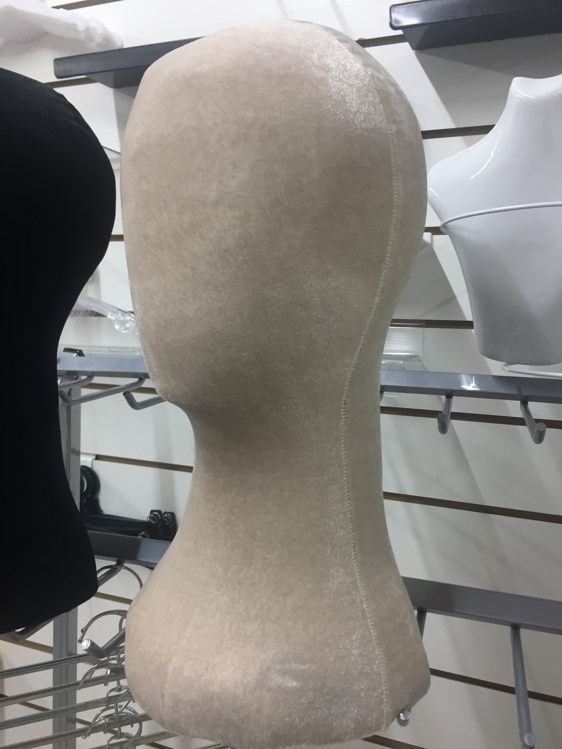 Cabeza de peluca de tela beige en exhibición en un establecimiento minorista.