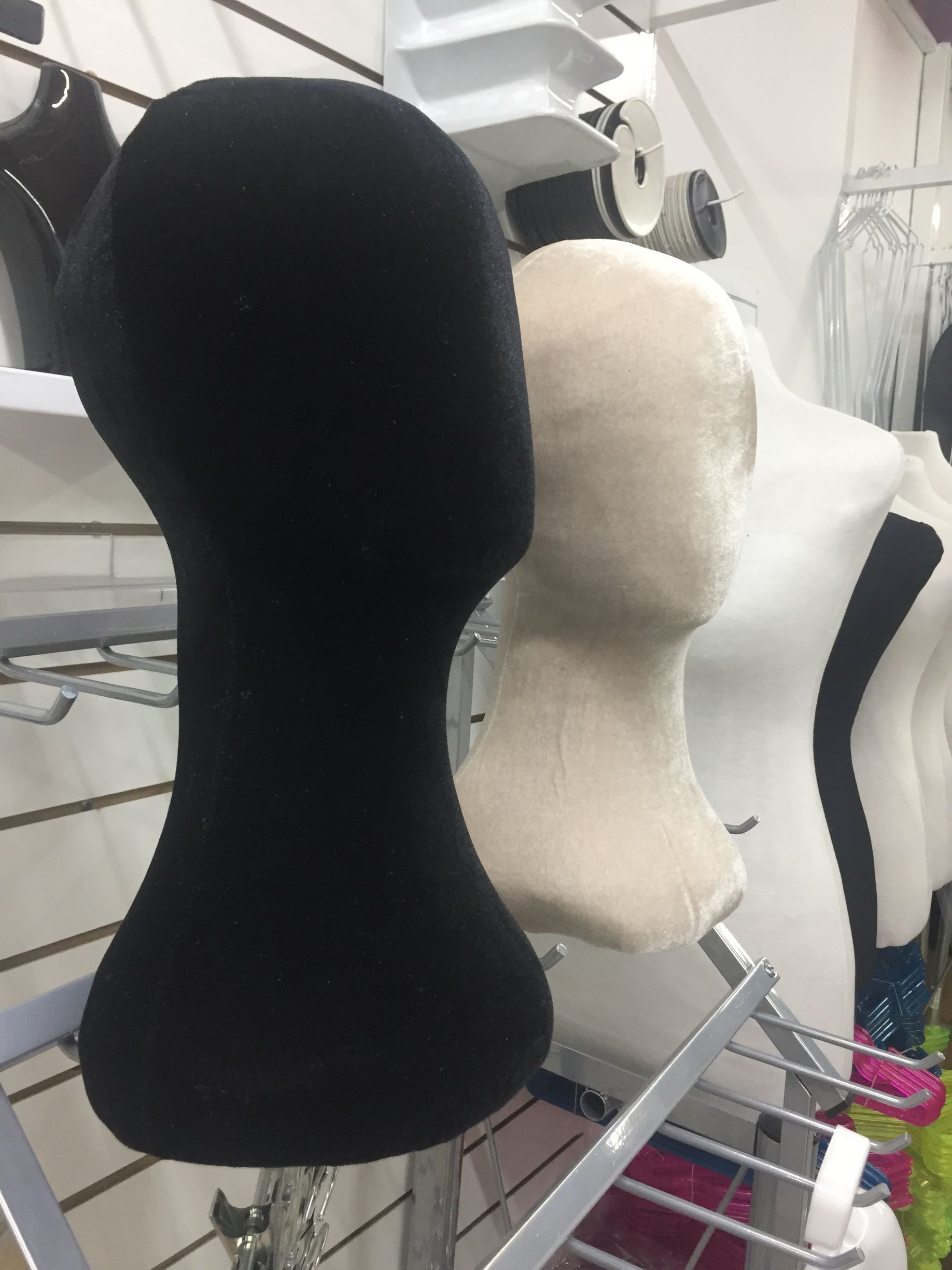 Cabezas de maniquí de color negro, beige y blanco, en fila, exhibidas en una tienda.