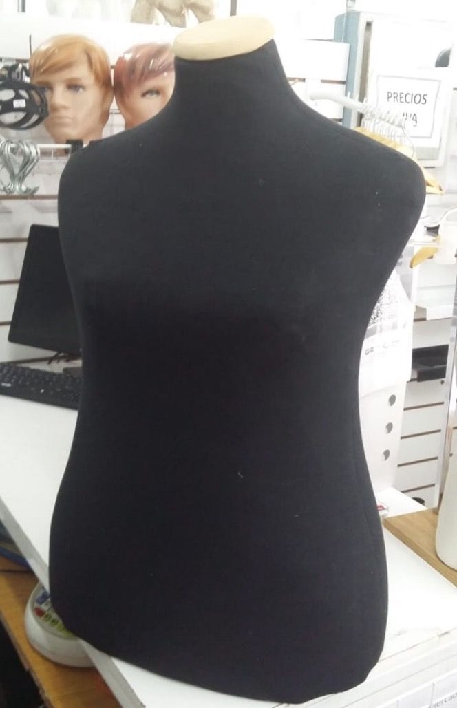 Maniquí de torso negro sobre superficie blanca, en el interior de una tienda.