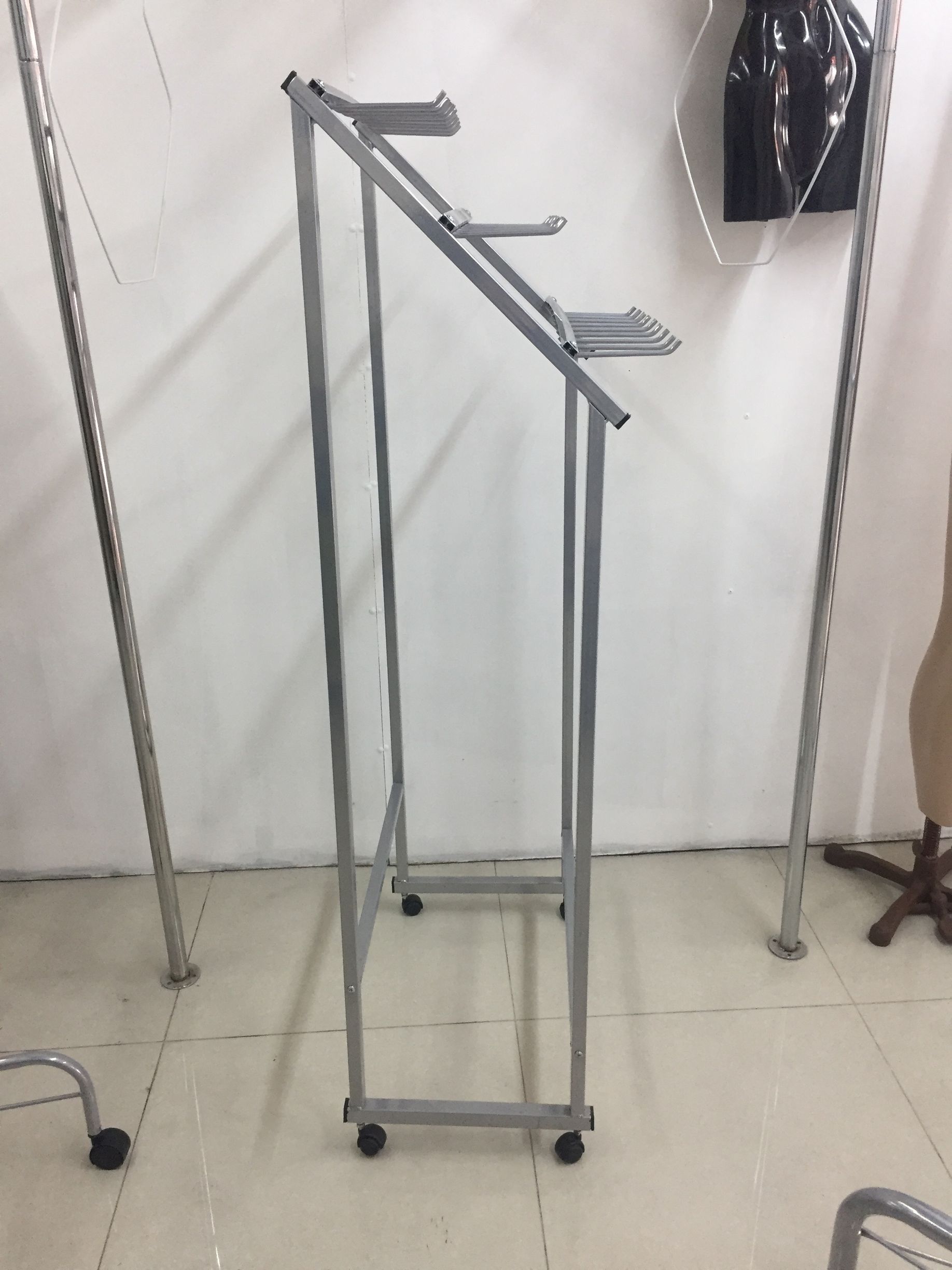 Perchero metálico con ruedas en una habitación blanca.