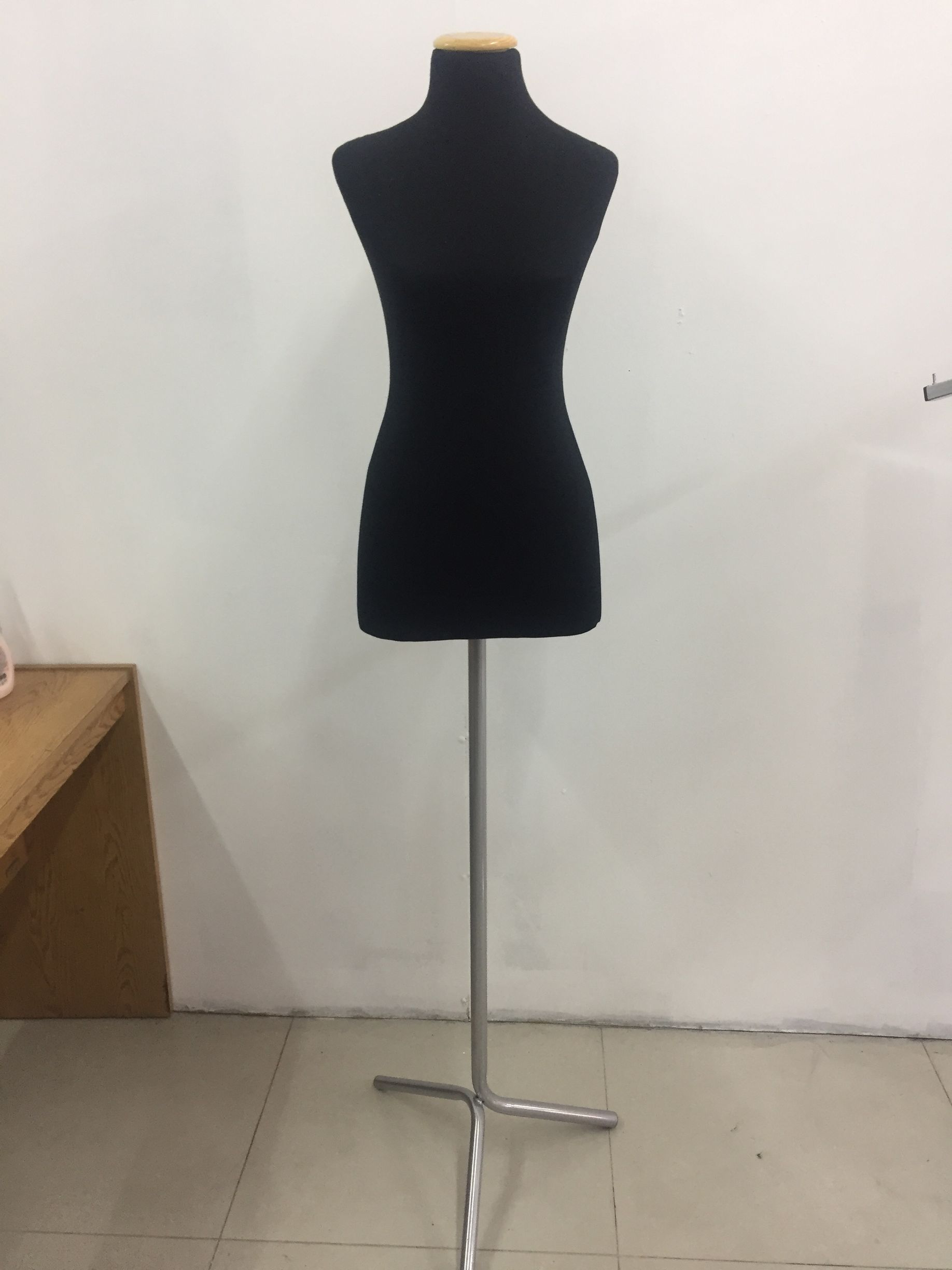 Figura de modista negra sobre soporte plateado delante de una pared blanca.