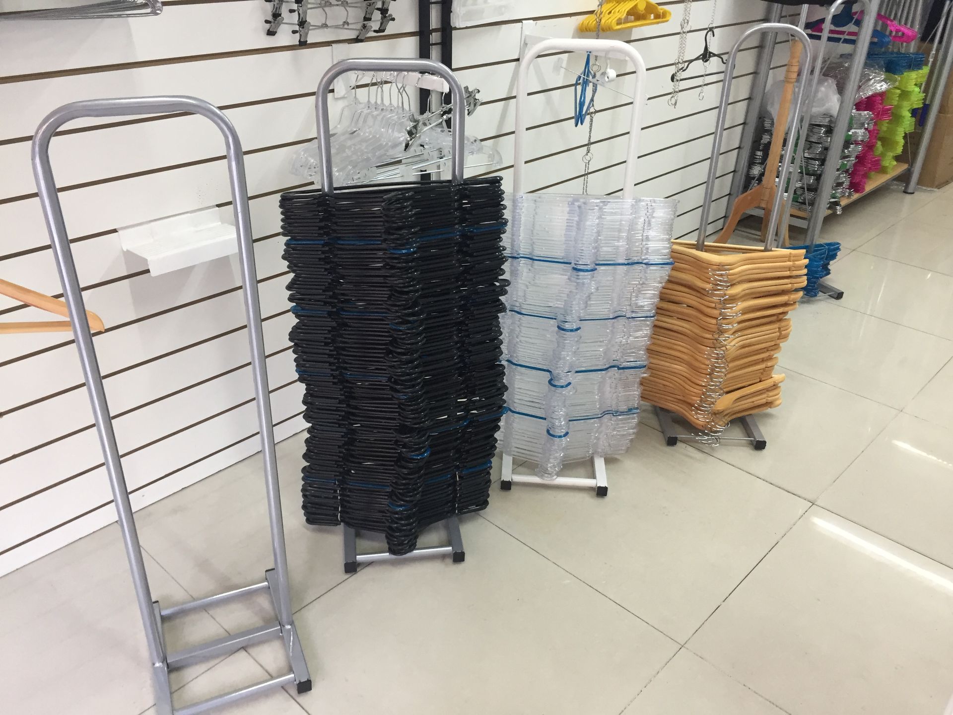 Estantes metálicos con escaleras y perchas en una tienda. Los estantes albergan perchas negras, transparentes y marrones.