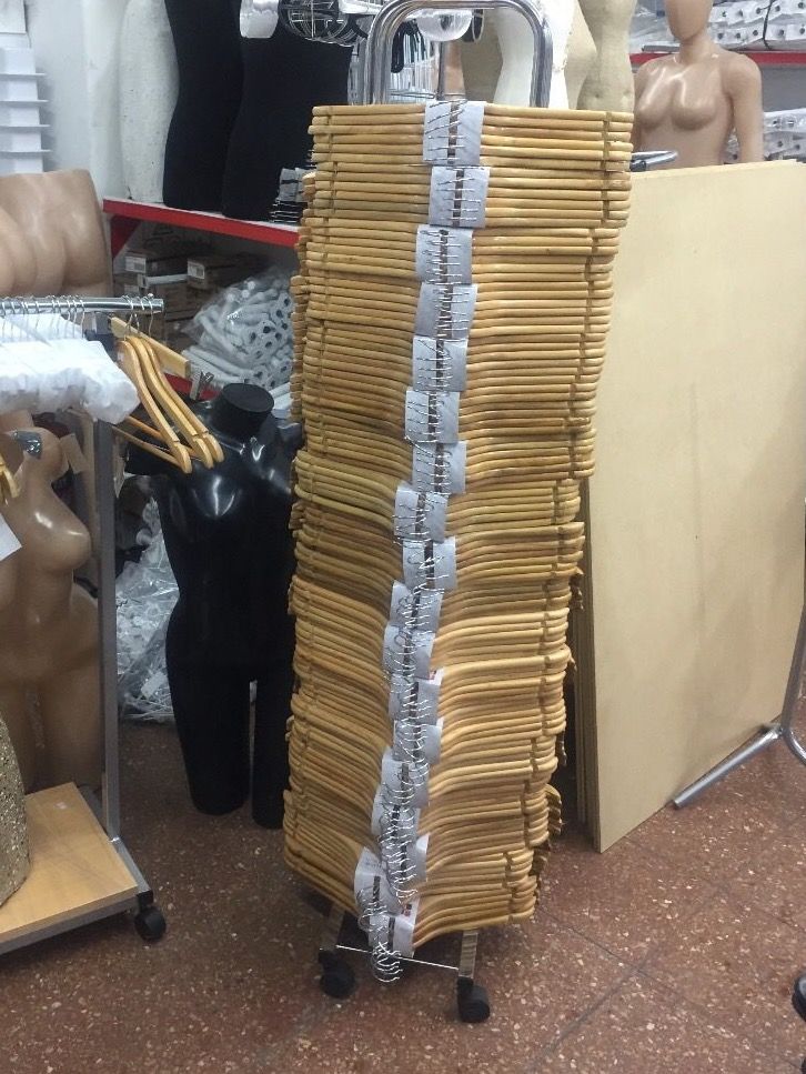 Perchas de ropa de madera apiladas en un estante con ruedas en una tienda minorista.