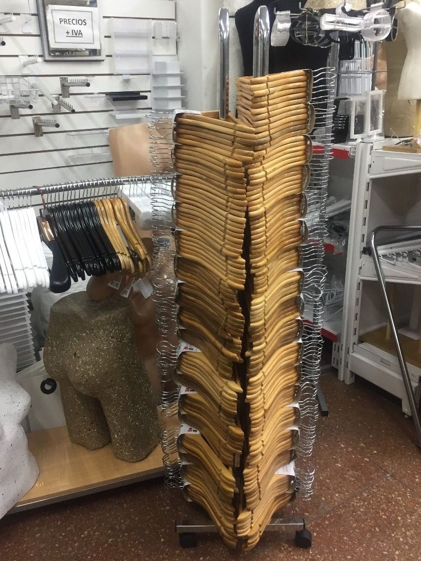 Un estante de exhibición alto lleno de perchas de madera para ropa en una tienda minorista.