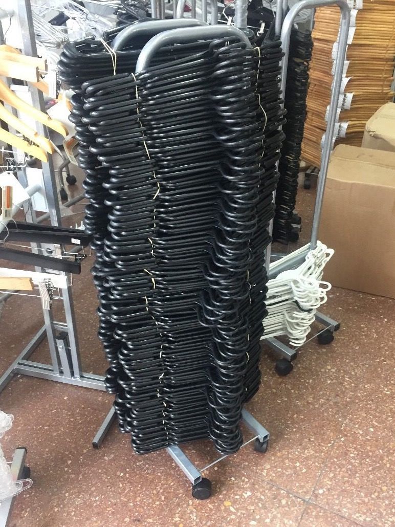 Perchas negras apiladas sobre un estante metálico rodante.