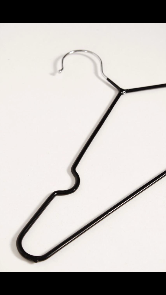 Percha de ropa de alambre negro sobre fondo blanco.