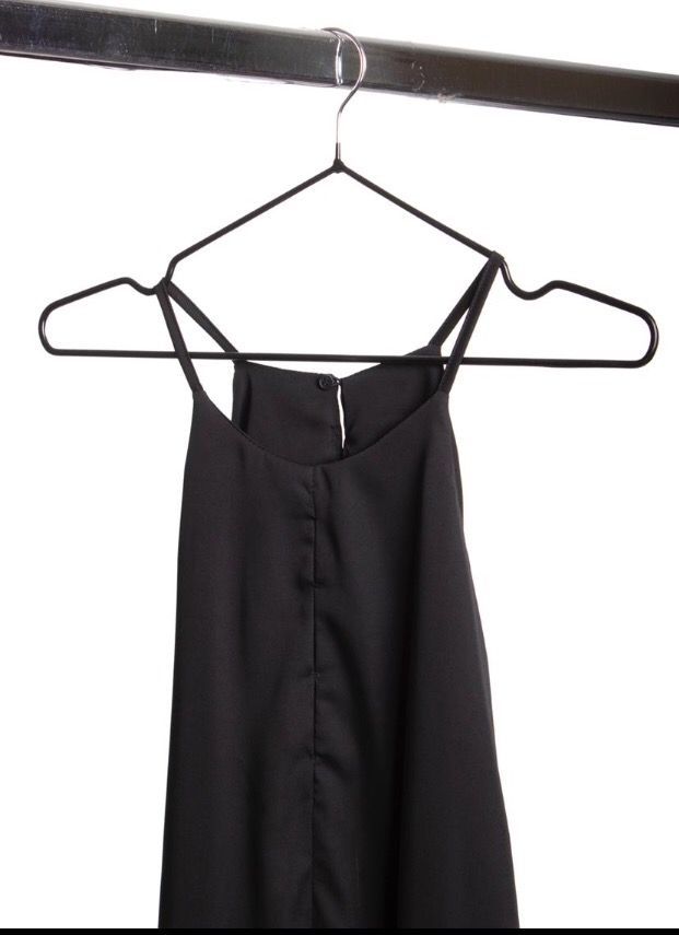 Vestido negro colgado en una percha de una varilla metálica.