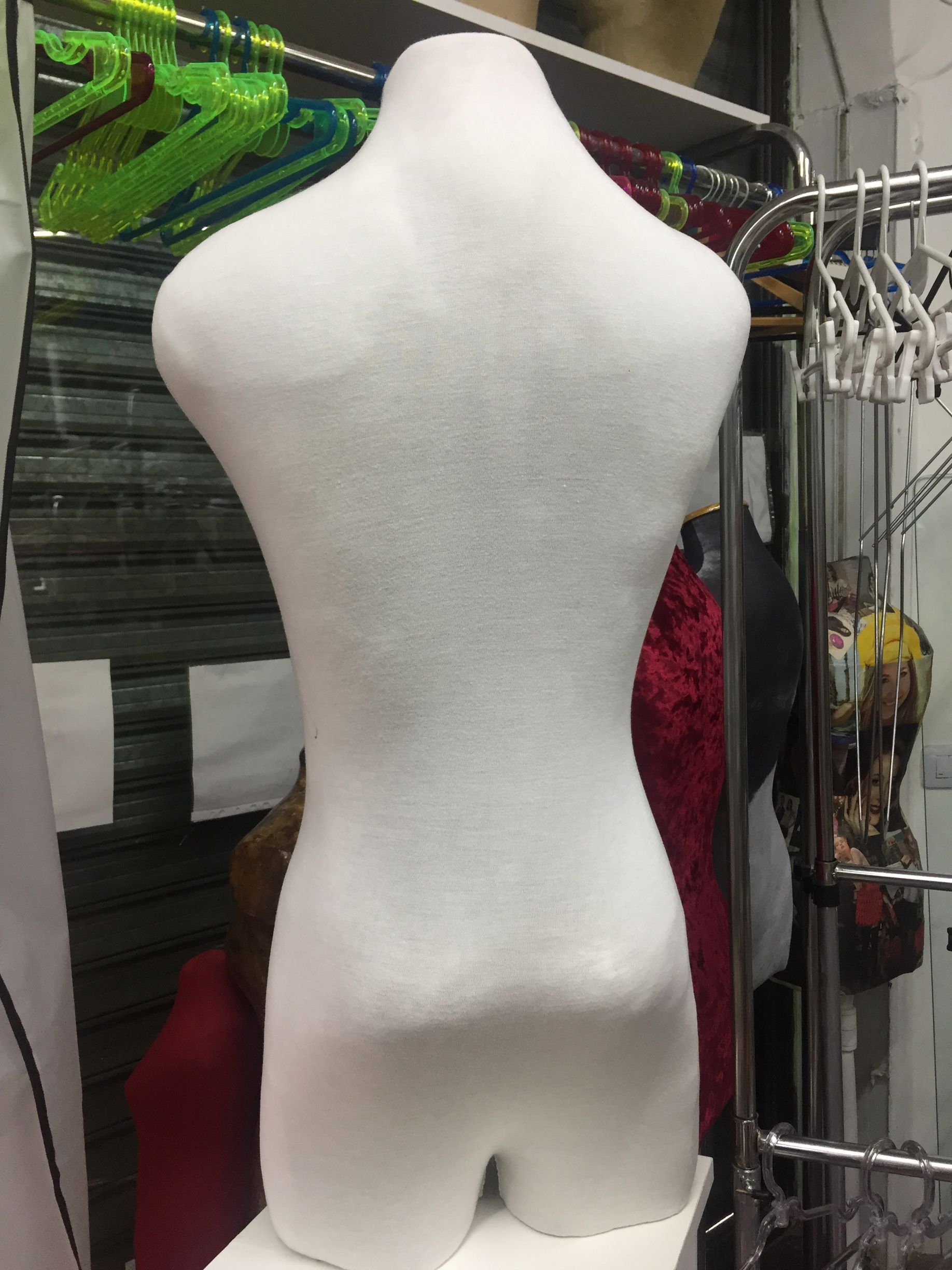 Torso de maniquí de tela blanca con espalda curvada.