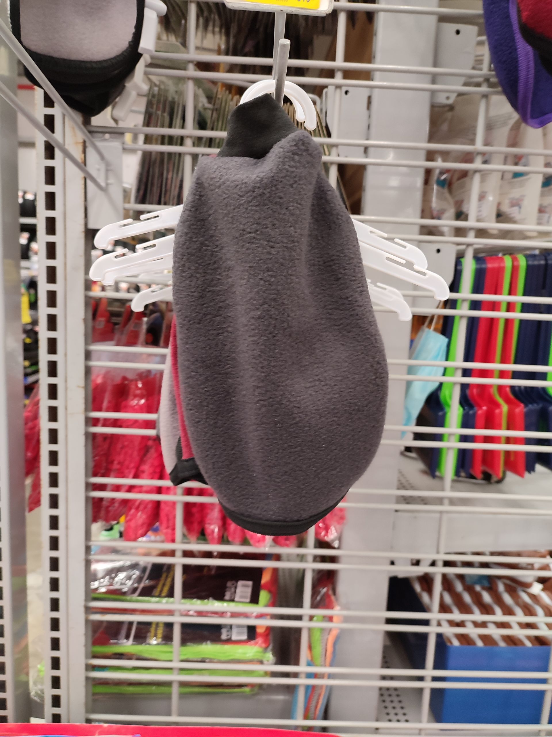Sombrero de polar gris colgado en un estante de una tienda, rodeado de otros artículos.