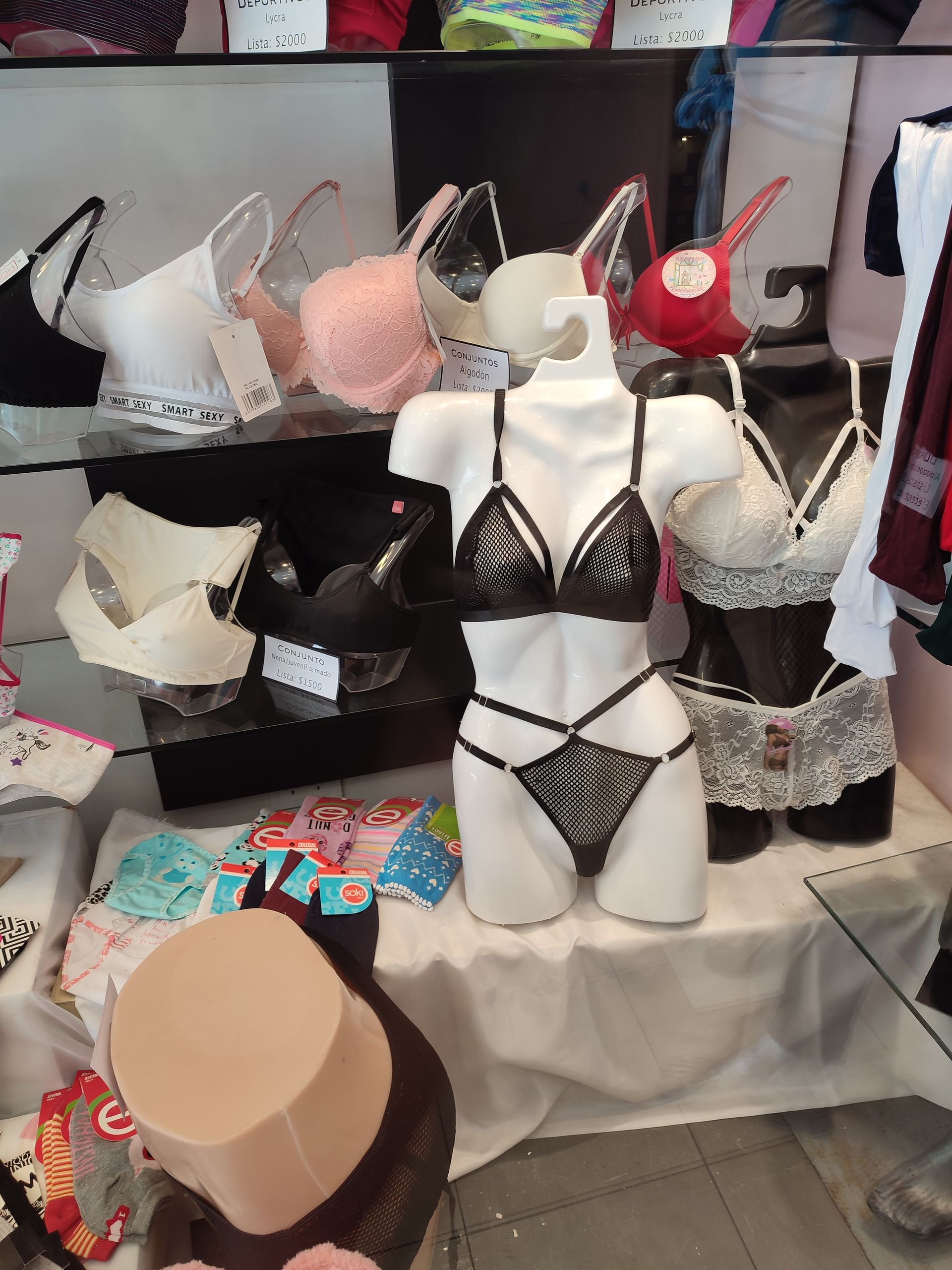 Exhibición de lencería en escaparate; se muestran maniquíes y sujetadores de varios colores.