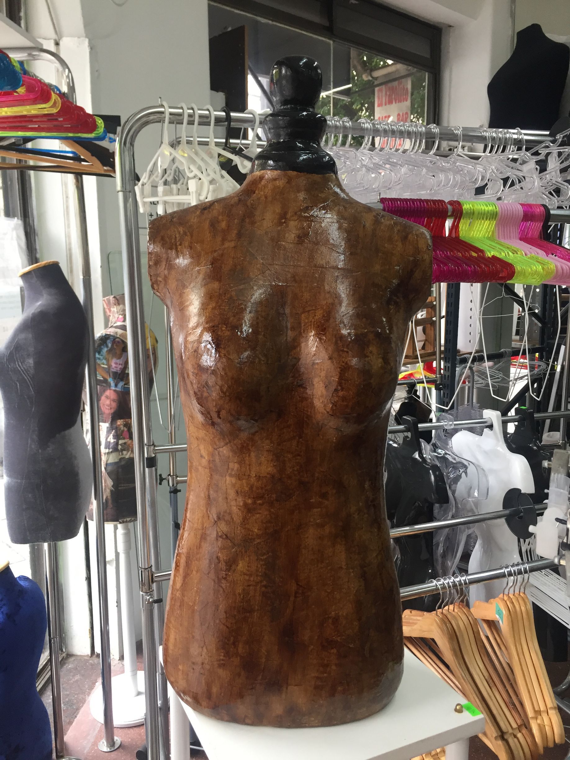 Maniquí de torso con textura marrón y cuello negro, en tienda.
