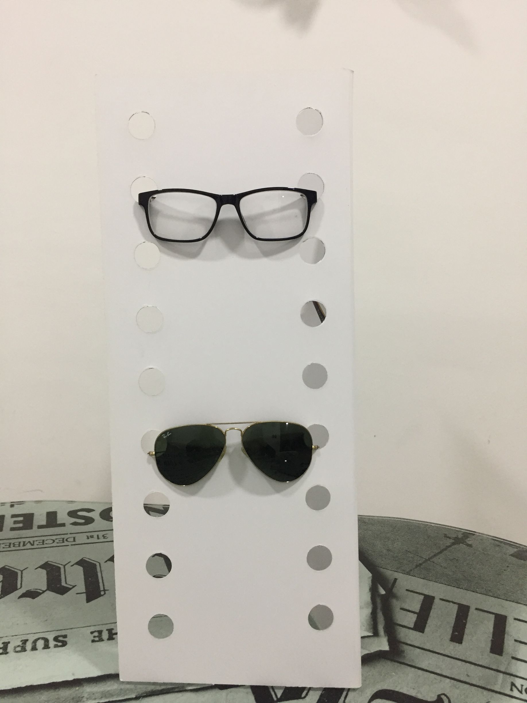 Gafas y gafas de sol sobre un tablero blanco con recortes circulares.