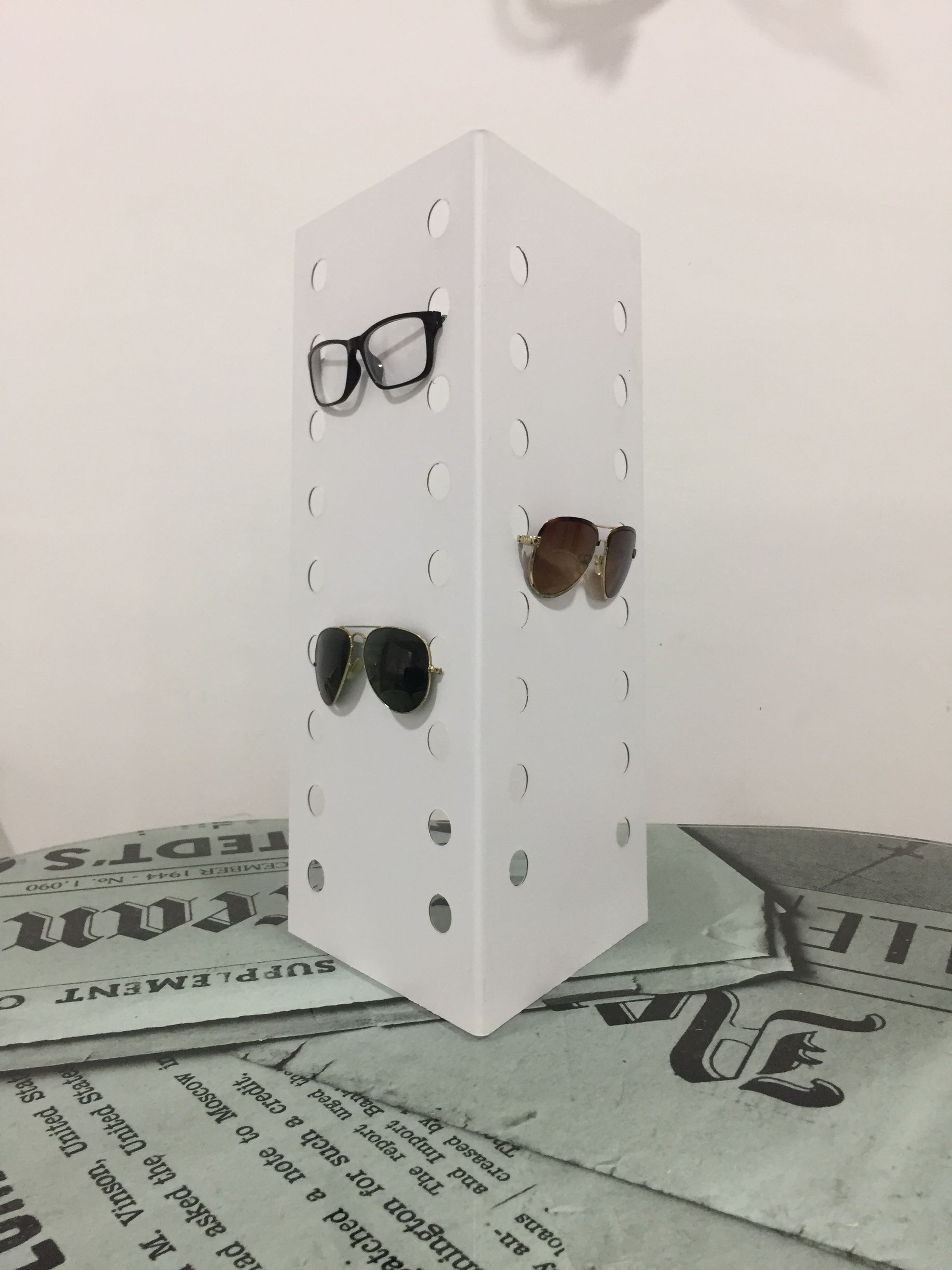 Expositor de gafas de color blanco con tres pares de gafas.