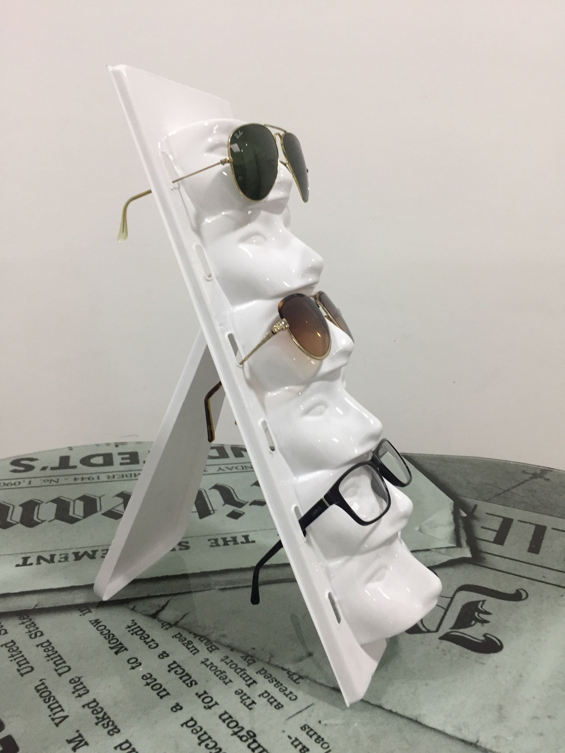 Gafas de sol expuestas en un soporte blanco, inclinado y con forma de busto. Se muestran tres pares de gafas.