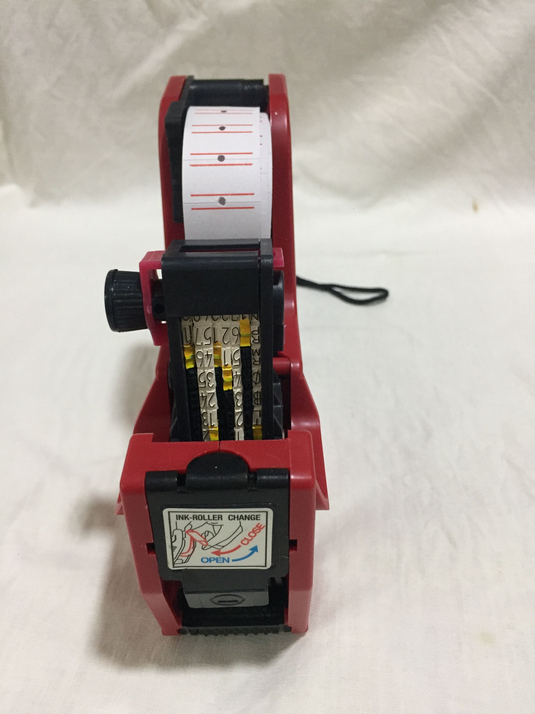 Etiquetadora de precios roja con un rollo de etiquetas cargado.