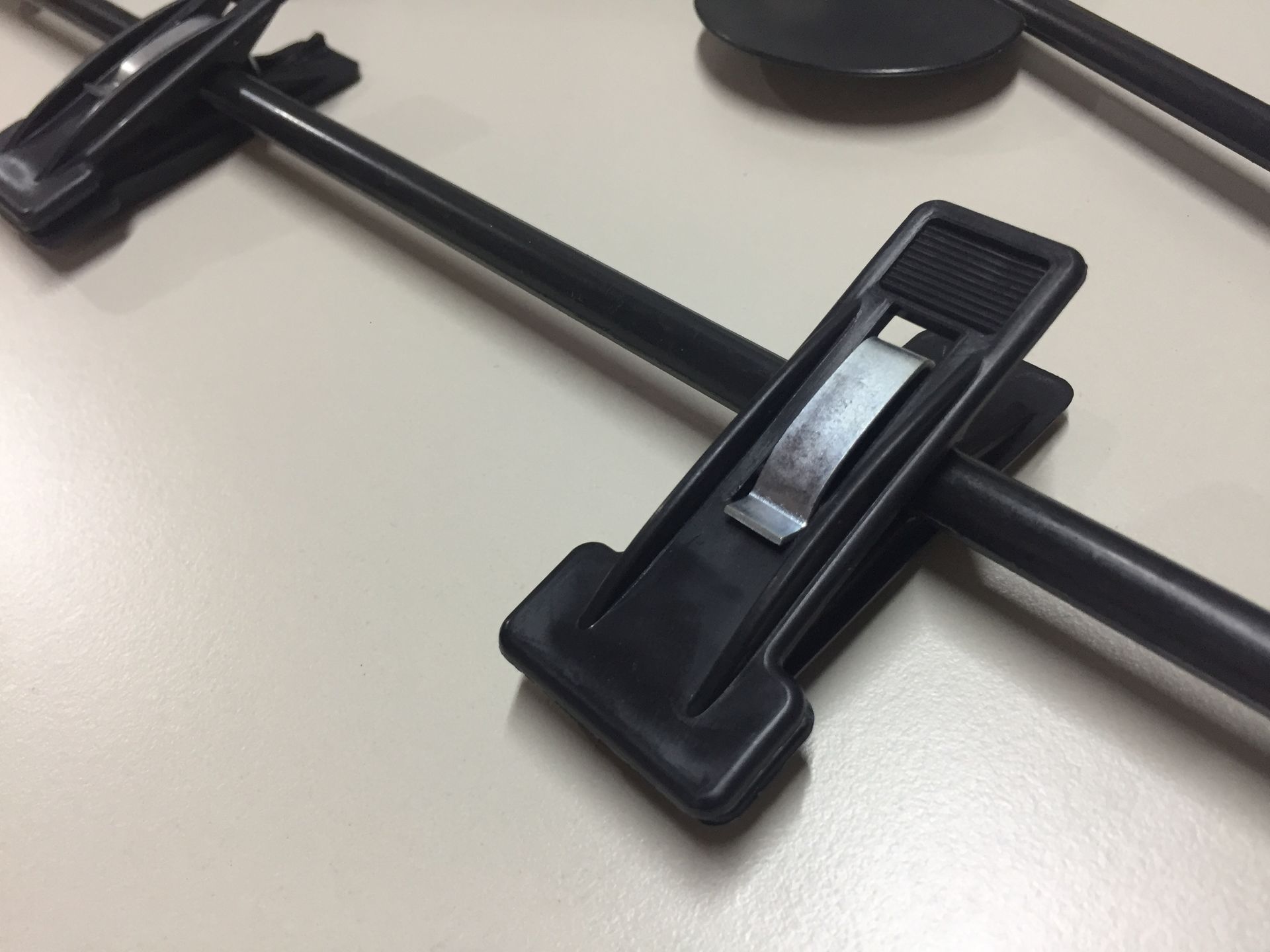 Perchas de plástico negro para faldas, con pinzas, sobre superficie clara.