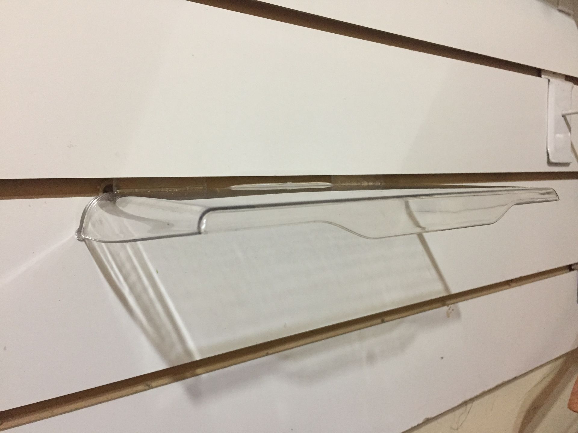 Estante de refrigerador de plástico transparente sobre estantería blanca.