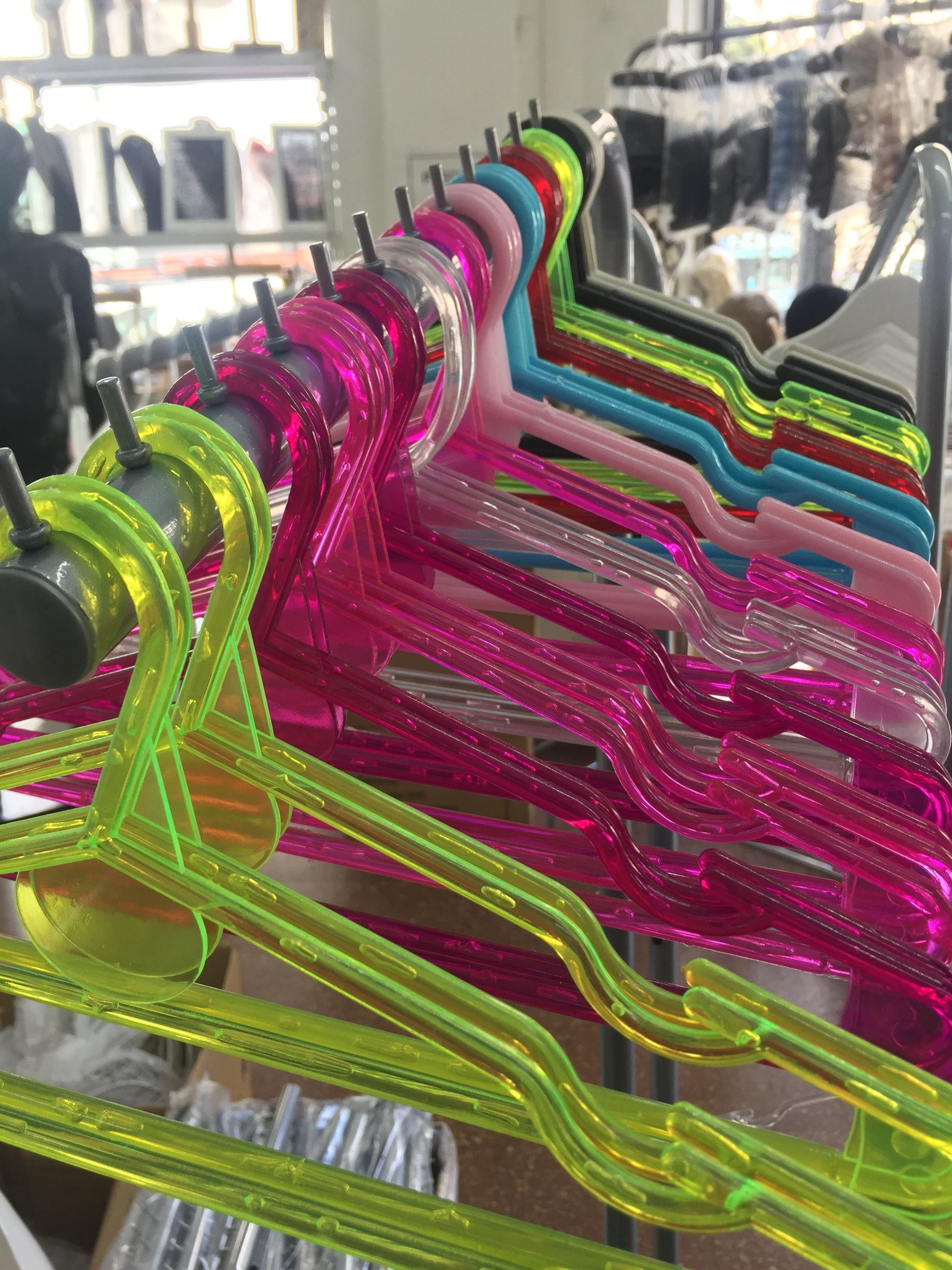 Perchas de plástico de colores para ropa en un estante de exhibición.