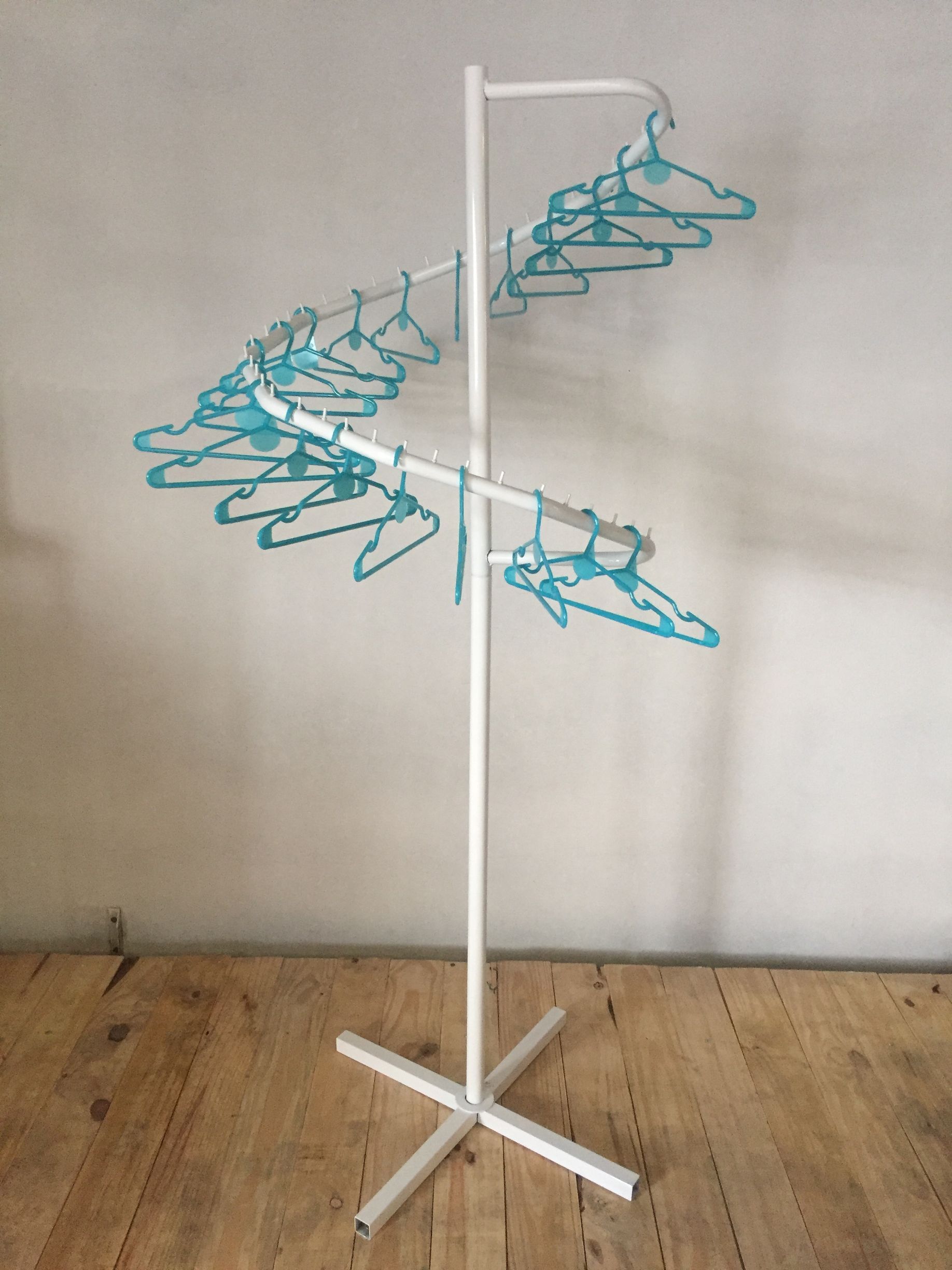Tendedero de ropa en espiral de color blanco con perchas de color verde azulado.