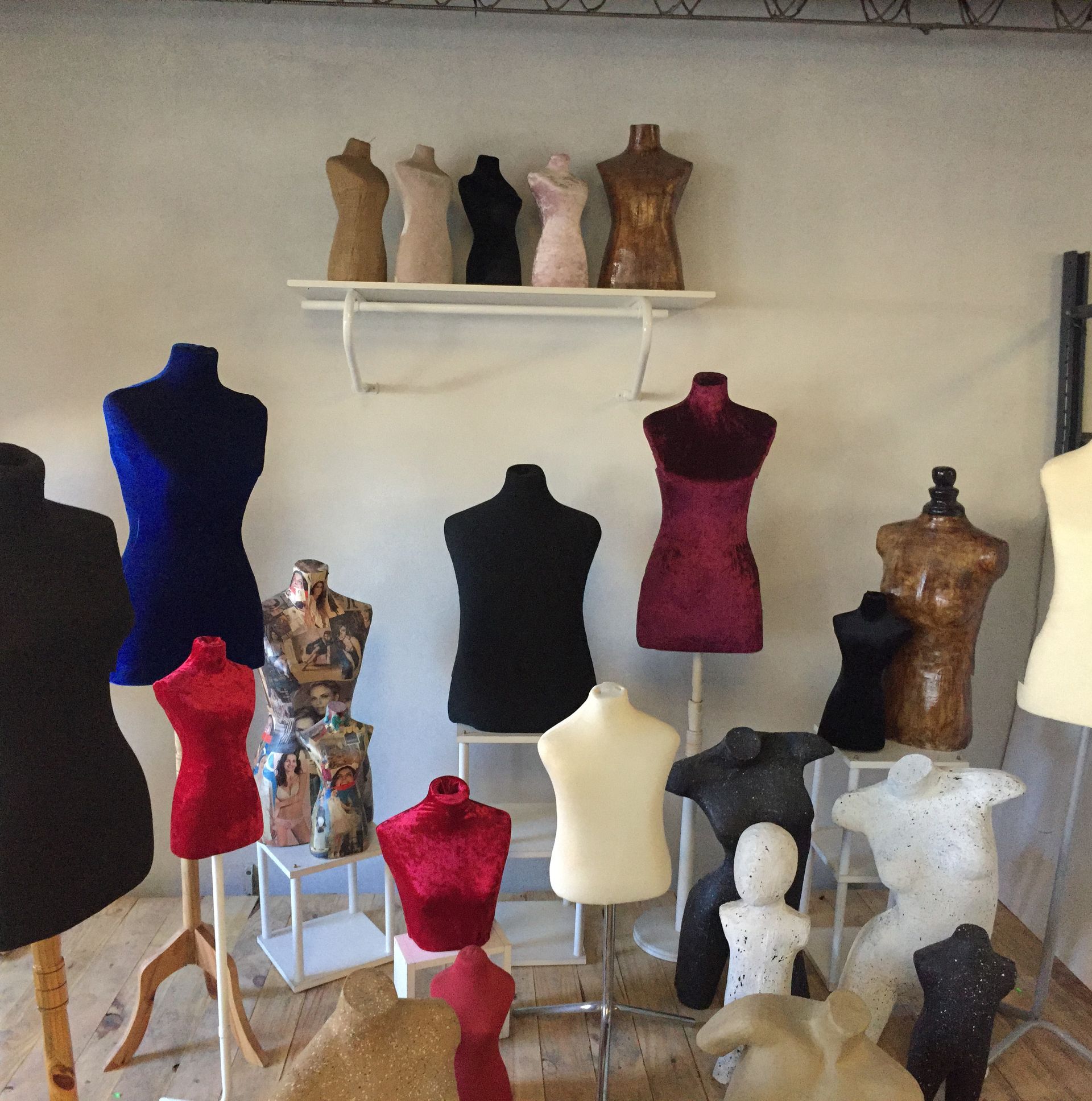 Exposición de diversos maniquíes de modista en un estudio. Los maniquíes presentan diferentes colores, texturas y estilos.