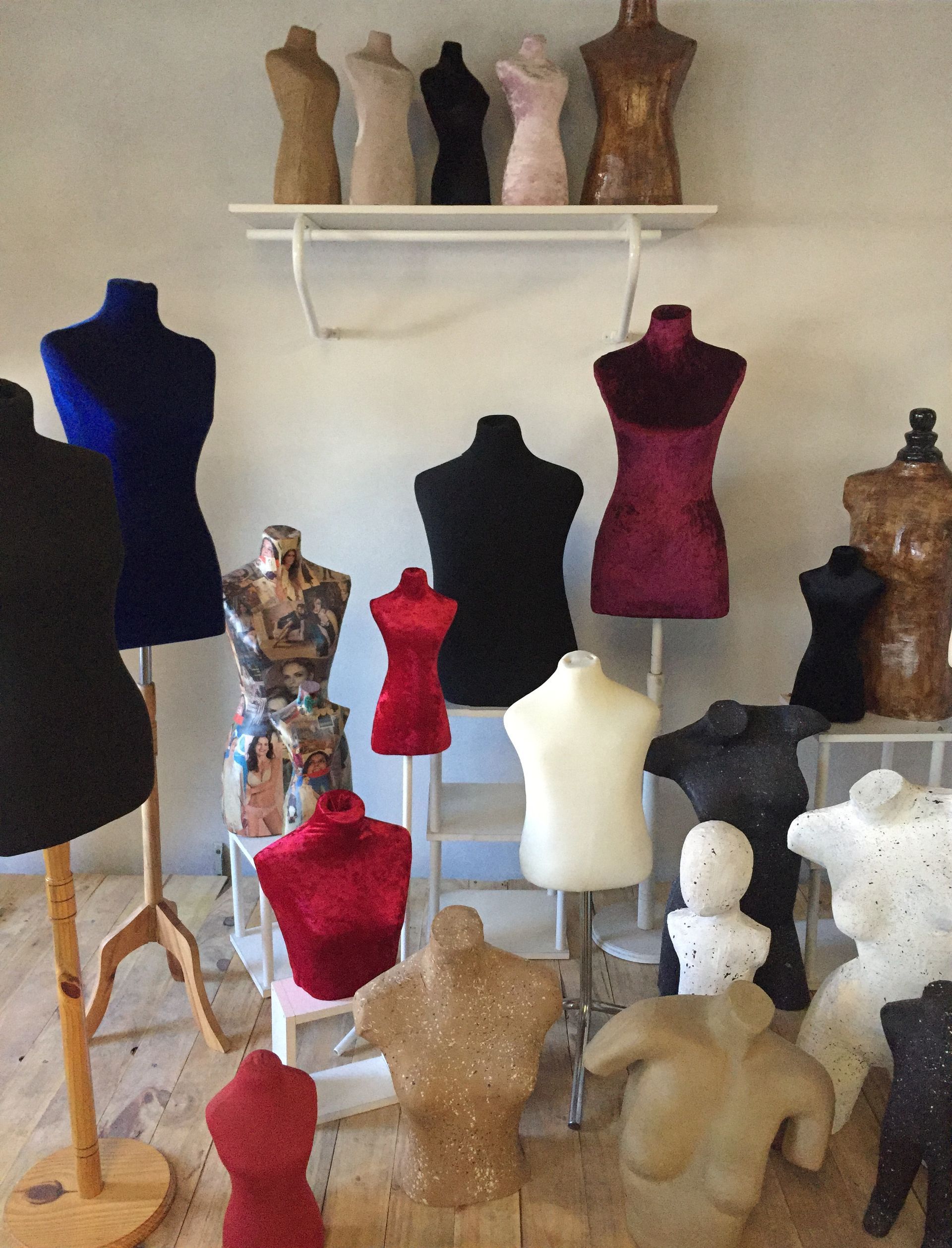 Colección de maniquíes de modista de varios colores, algunos con soportes.