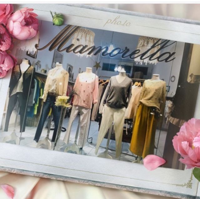 Escaparate de la boutique Miamorella con maniquíes con trajes pastel, rodeados de flores rosas.