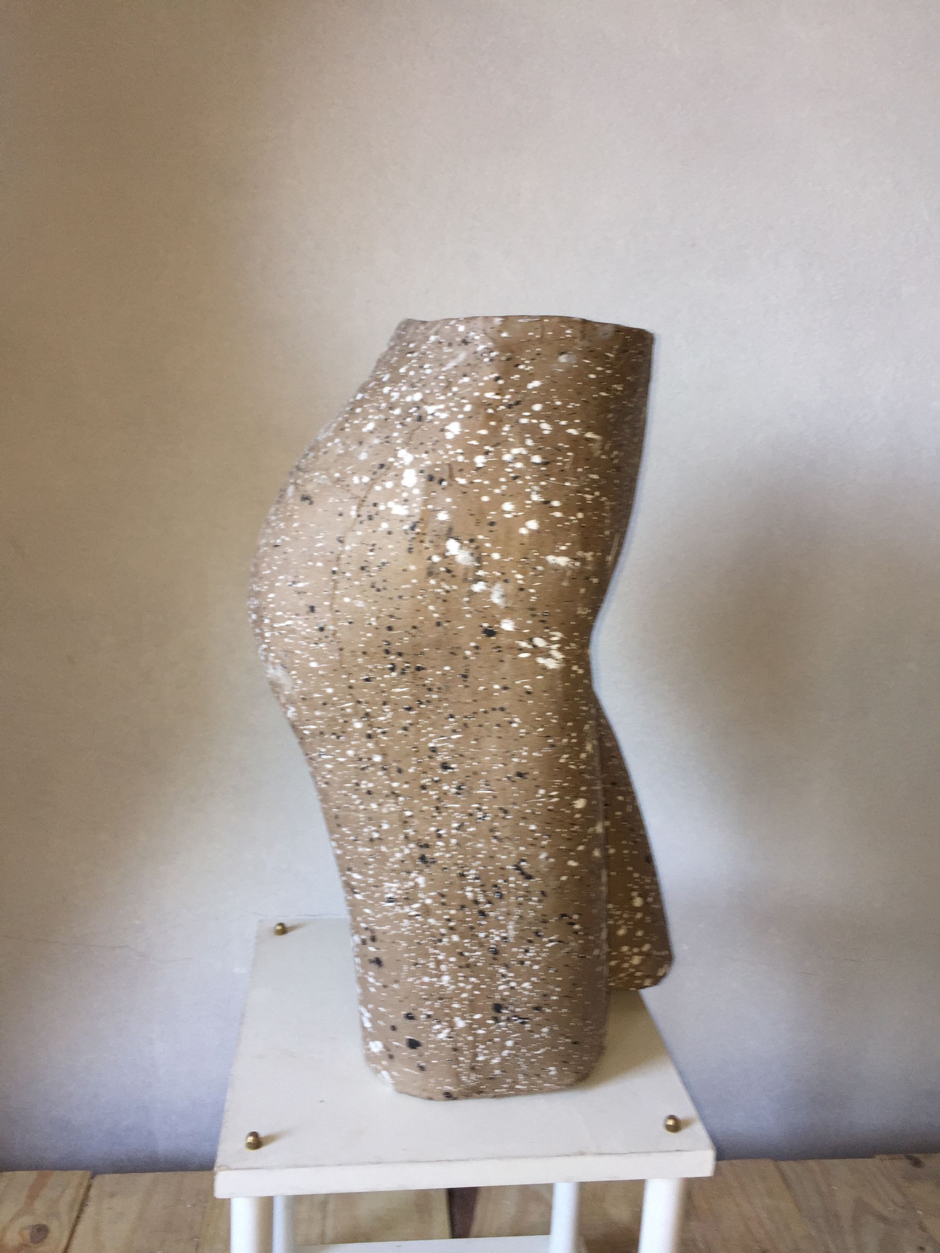 Escultura de un torso, realizada en material moteado de color claro