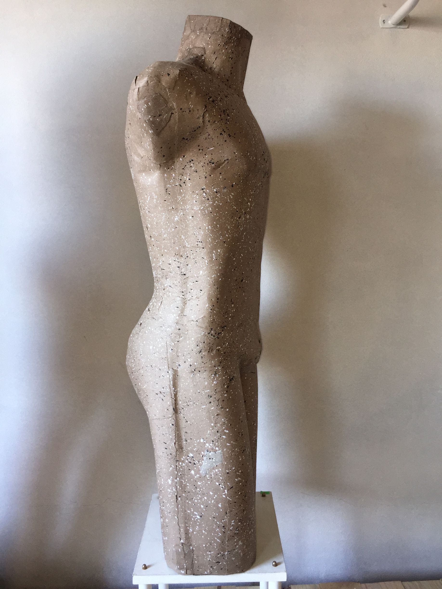 Escultura de un torso masculino, de textura moteada de color canela