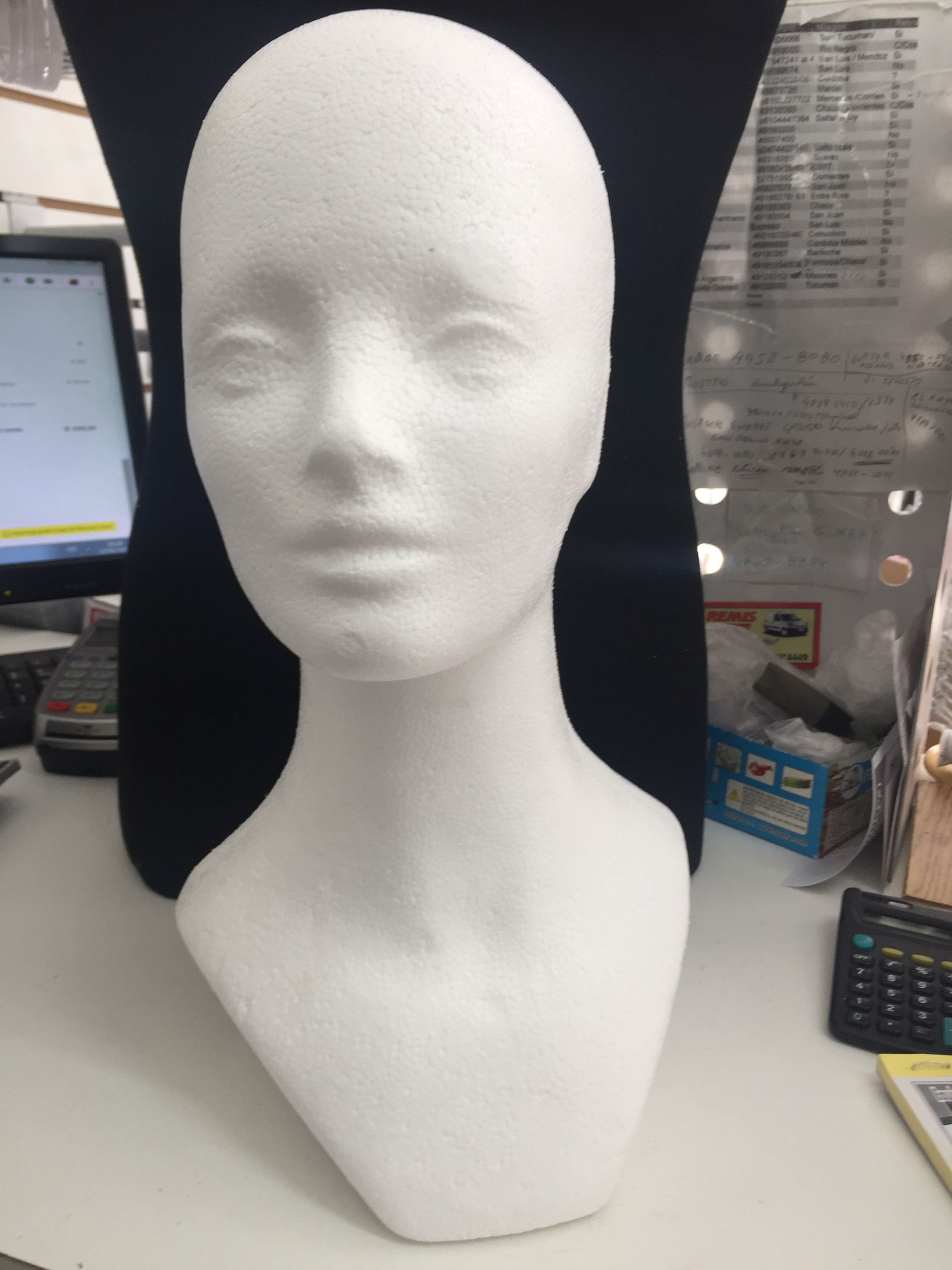 Cabeza de maniquí de espuma blanca, con rasgos lisos y en blanco, sobre un escritorio blanco.