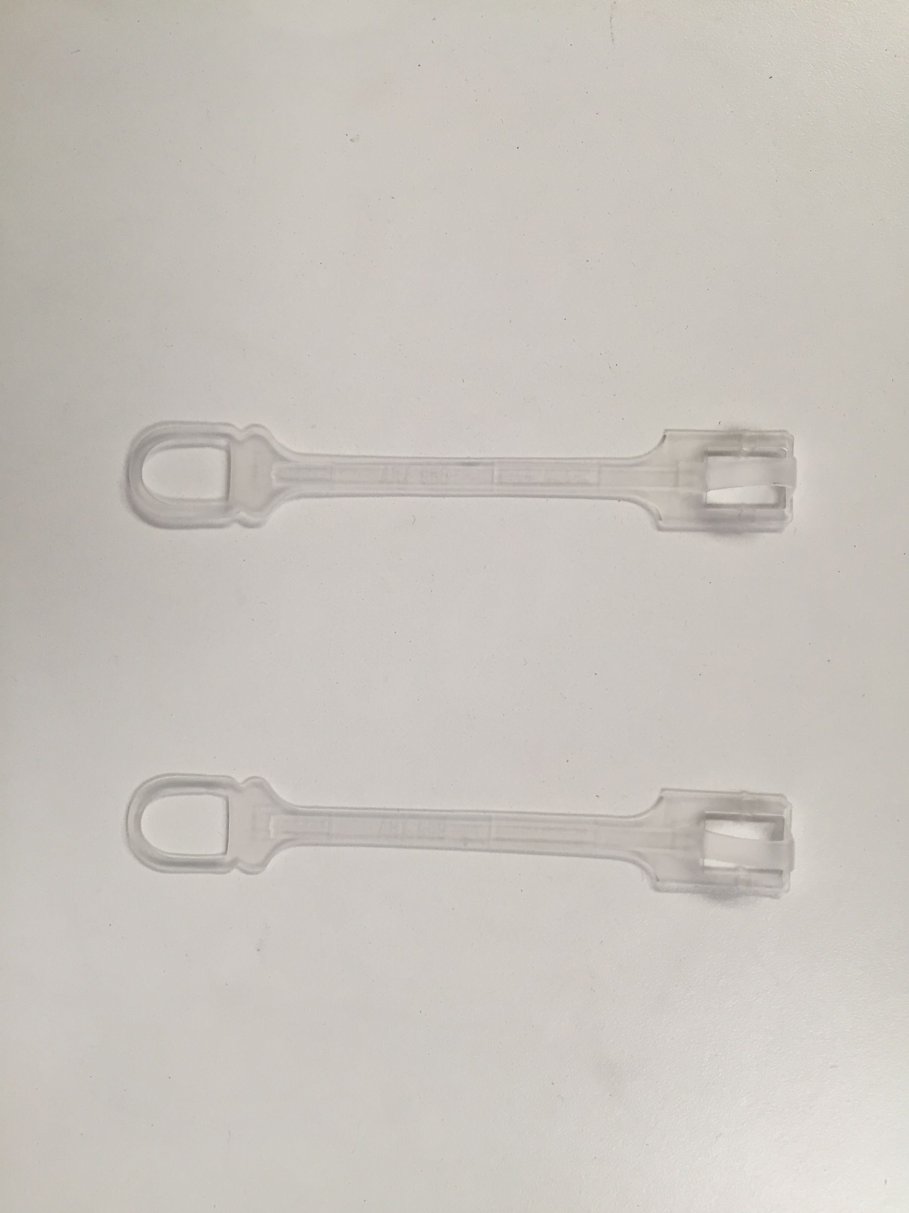 Dos amarres de plástico transparente colocados sobre una superficie blanca.