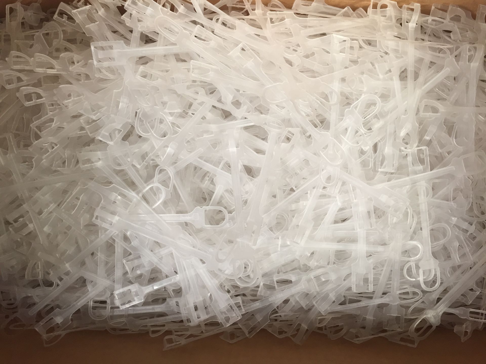 Una caja llena de muchas piezas de plástico pequeñas y translúcidas, posiblemente sujetadores o clips.