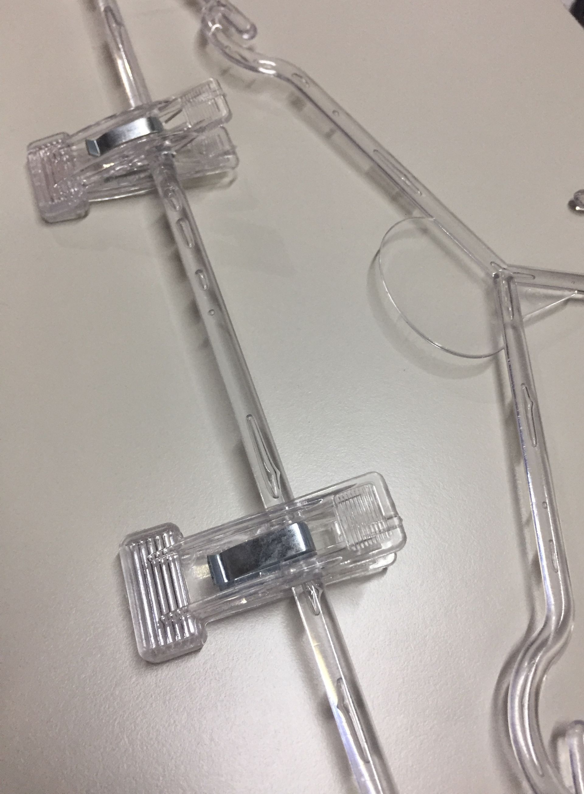 Perchas de falda de plástico transparente sobre una superficie blanca, vista de cerca.