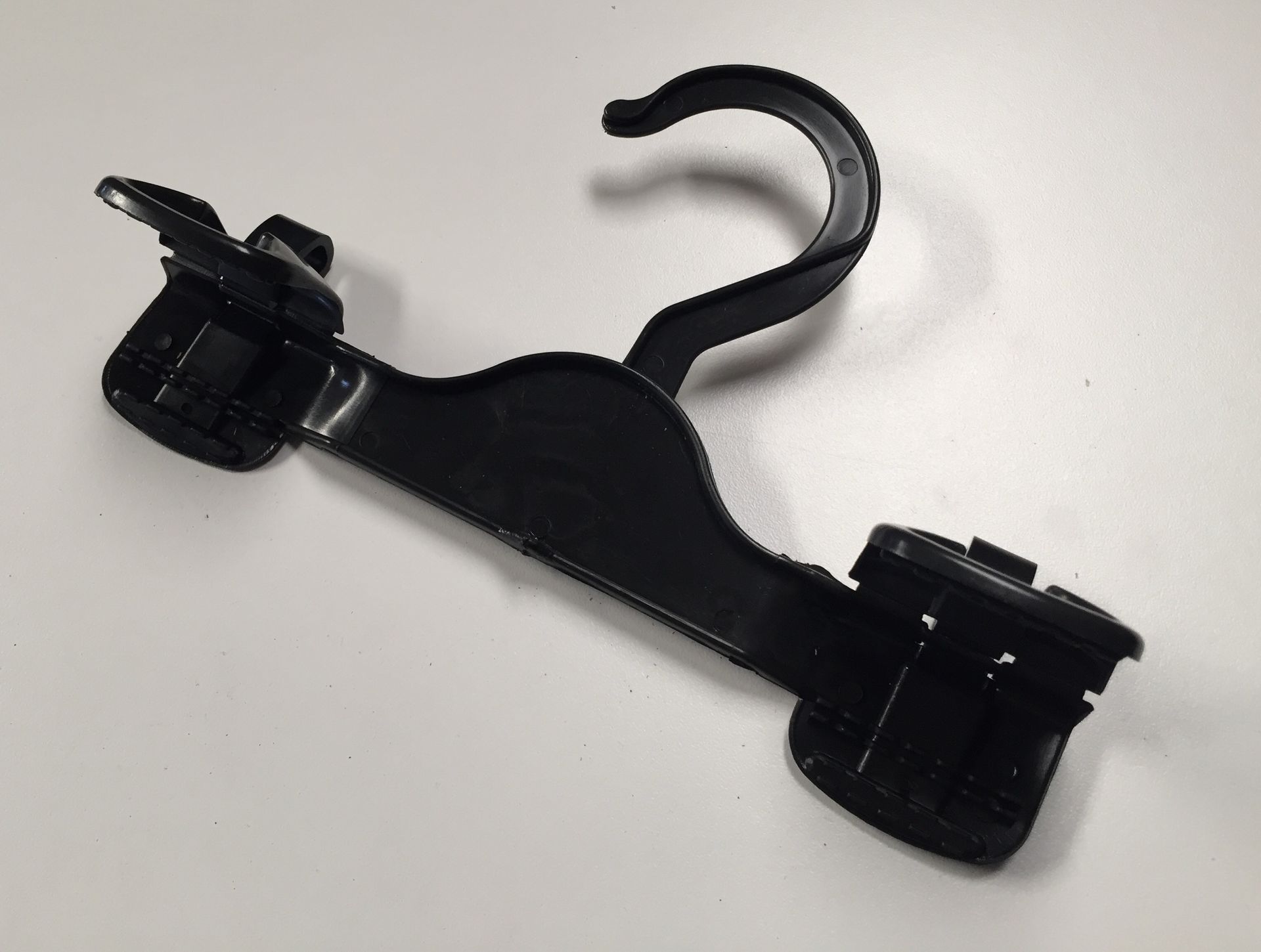 Percha para asiento de coche de plástico negro con gancho y pinzas.