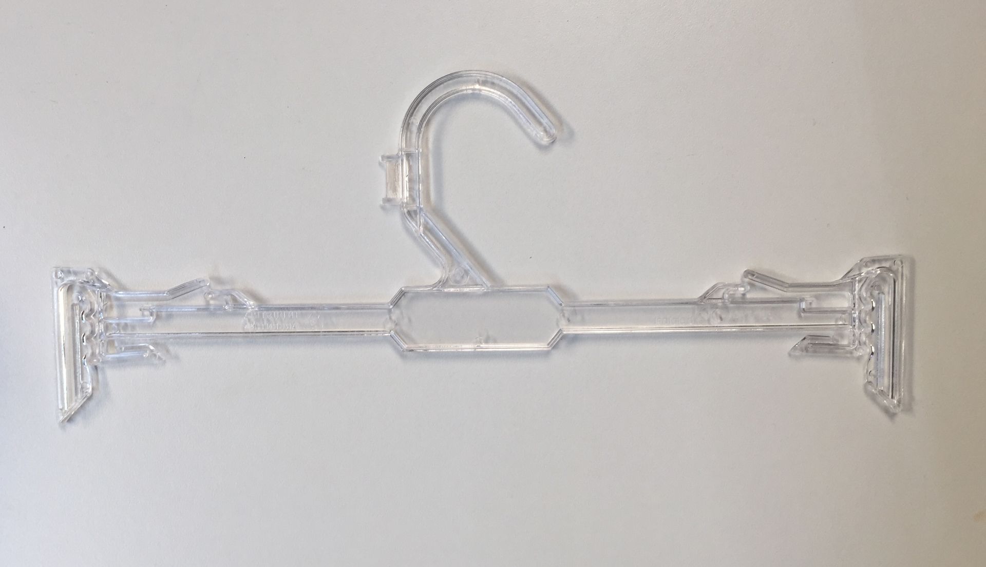Percha para pantalones de plástico transparente con clips ajustables.