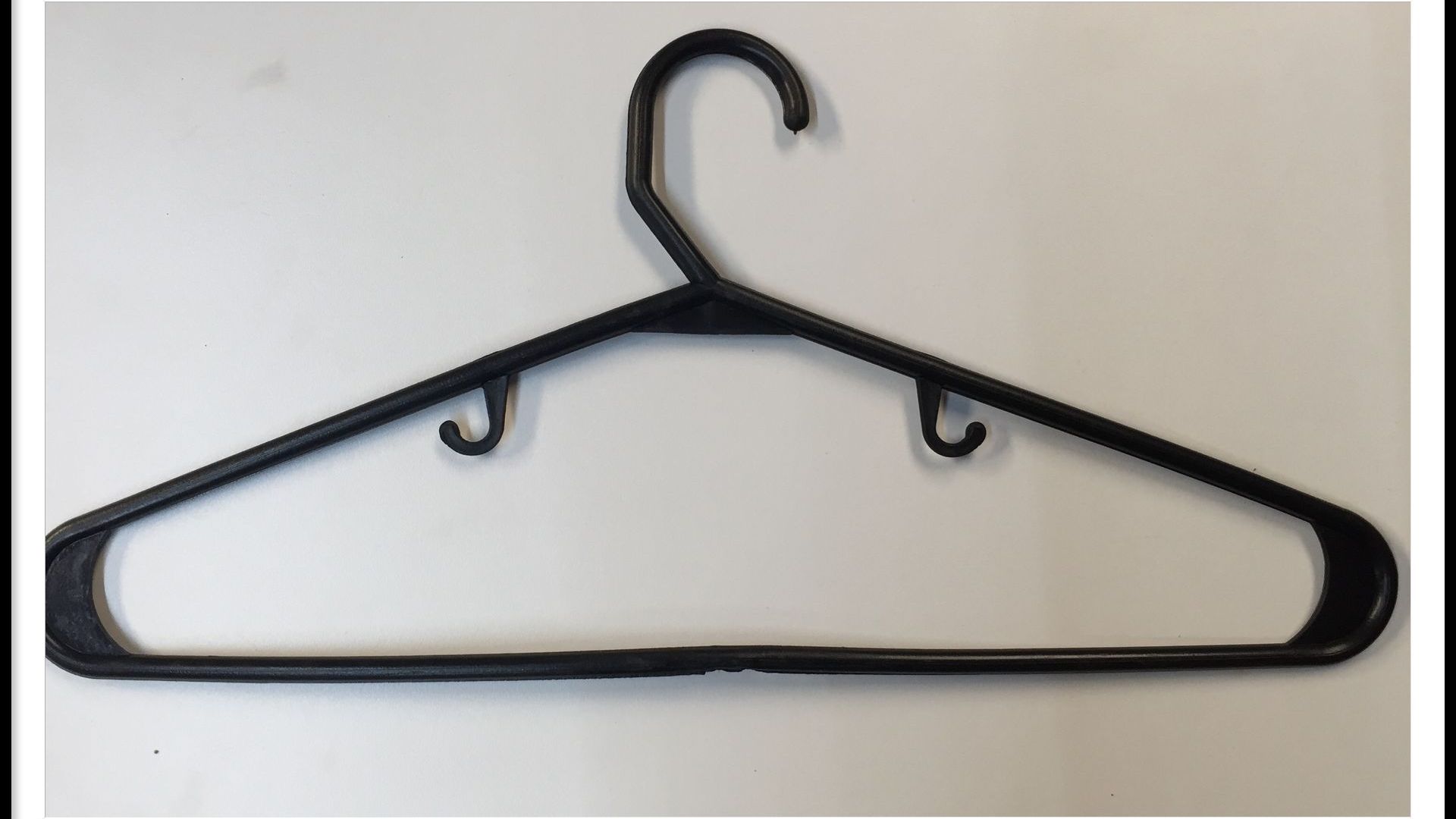 Percha de ropa de plástico negra con gancho y muescas.