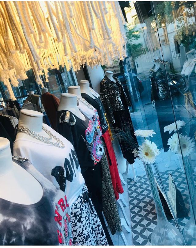 Escaparate de tienda de ropa con maniquíes luciendo tops, collares y pantalones de moda.