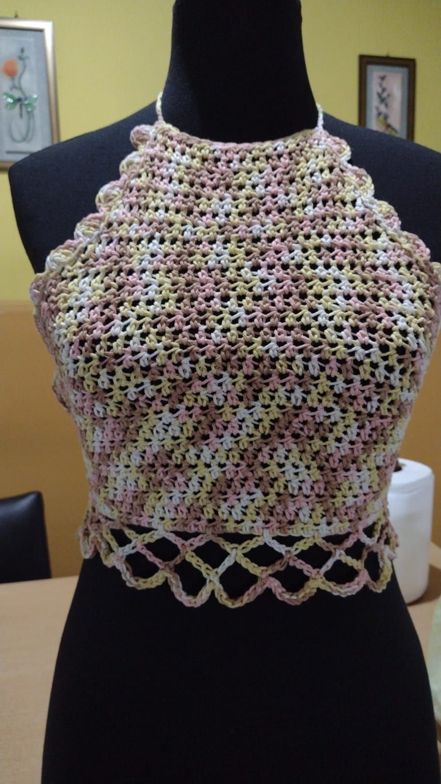 Top halter tejido a crochet en tonos pastel sobre maniquí, con borde inferior decorativo.