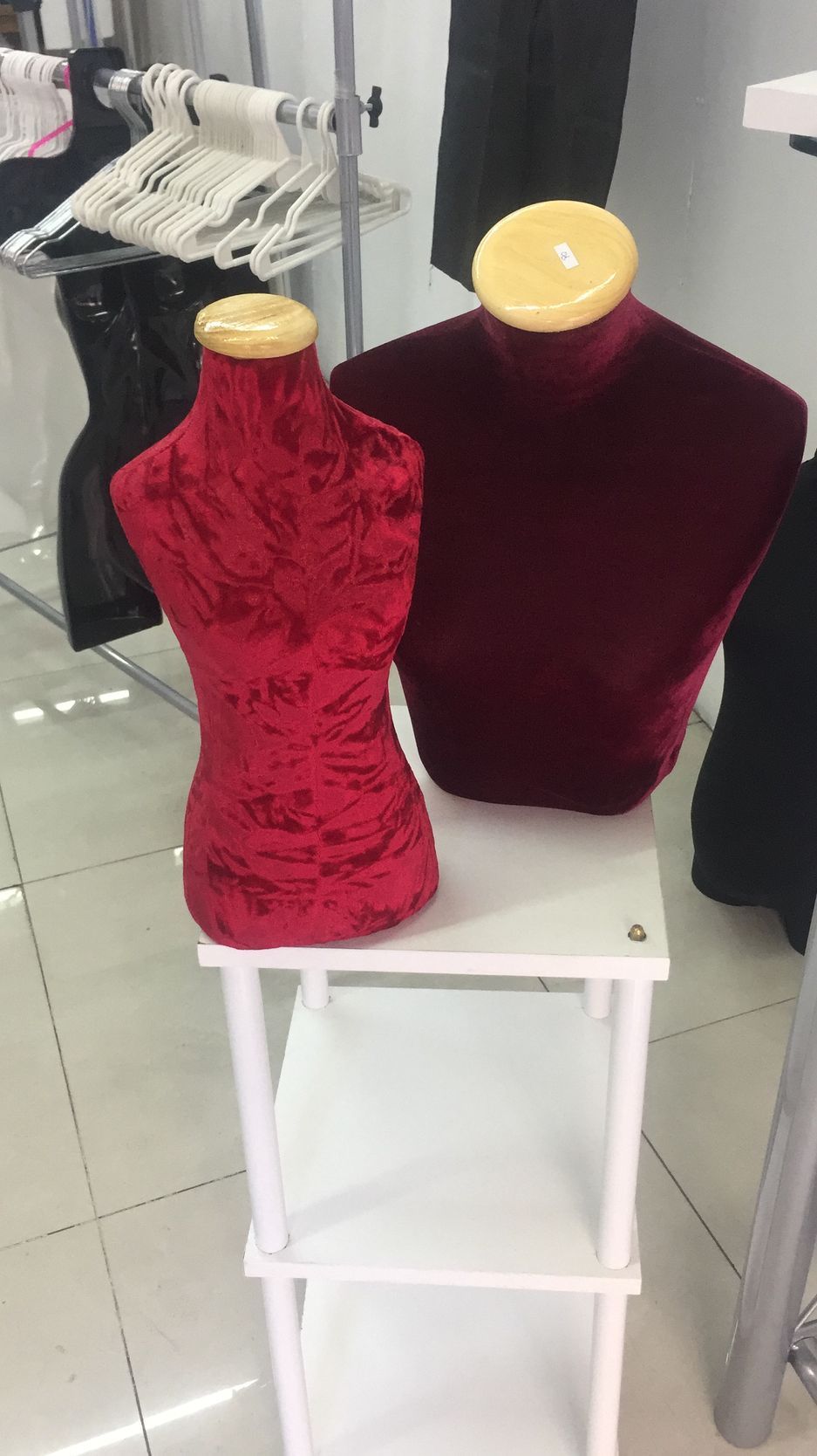 Dos maniquíes de terciopelo rojo sobre un estante blanco. El interior de una tienda de ropa es el escenario.