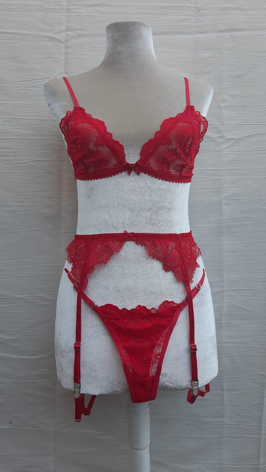 Conjunto de lencería de encaje rojo sobre maniquí blanco, que incluye sujetador, liguero y tanga.
