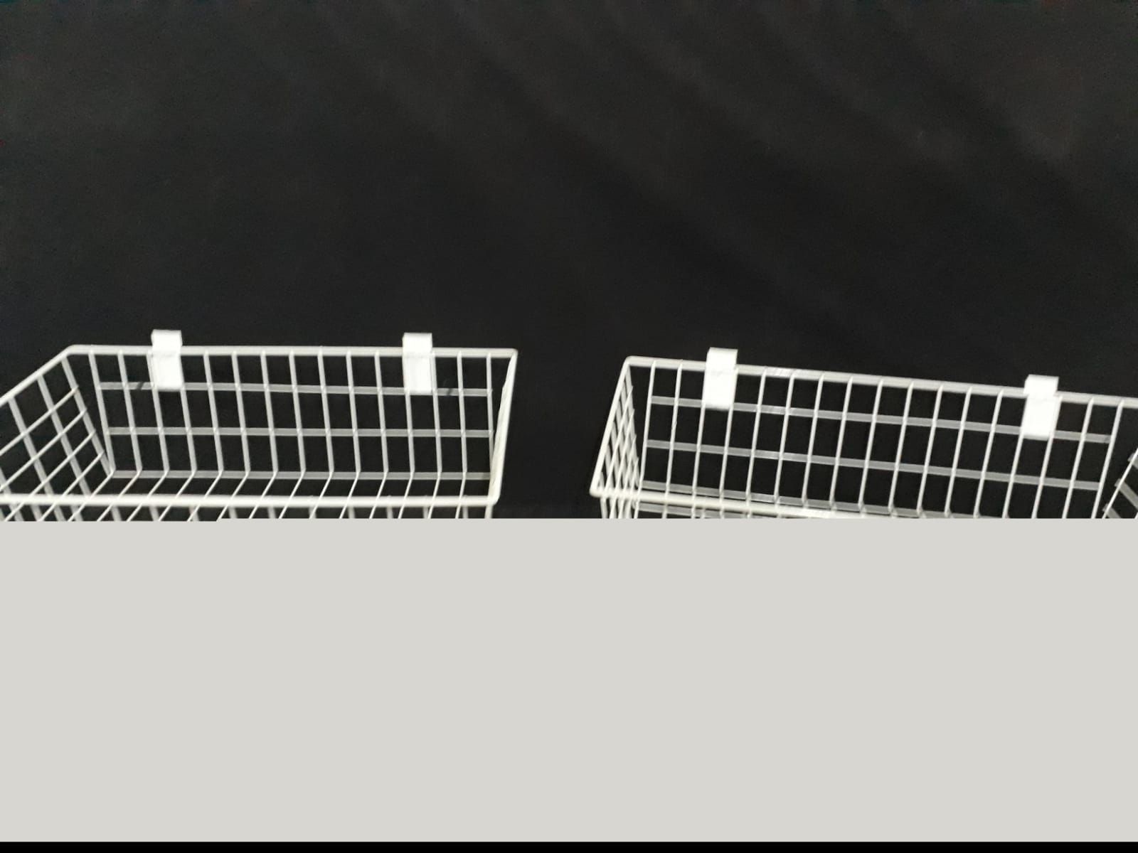 Dos cestas de alambre blancas con clips, sobre un fondo negro.