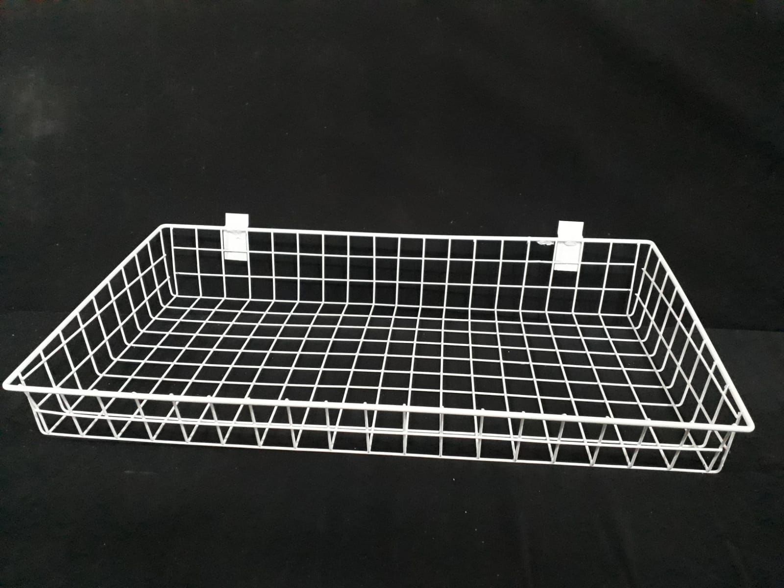 Cesta de alambre blanca con dos soportes para colgar sobre un fondo negro.