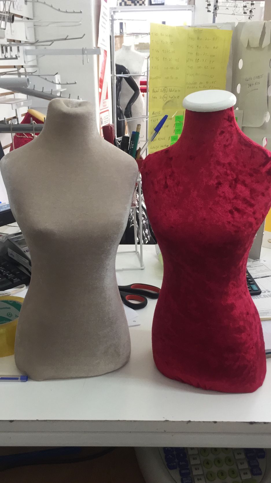 Dos maniquíes, uno de color canela y otro de terciopelo rojo, se encuentran uno al lado del otro sobre una superficie blanca.