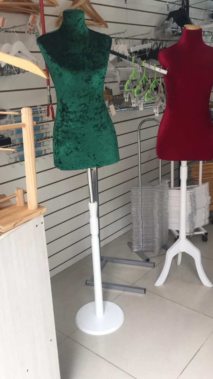 Dos maniquíes de modista, uno verde y otro rojo, sobre soportes blancos, en el interior.