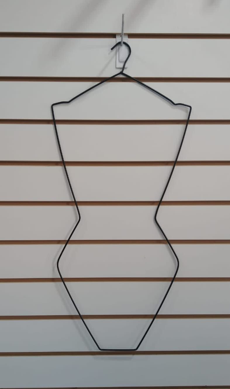 Percha de alambre para maniquíes colgada en una pared de listones blancos.